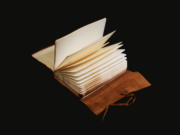 Quaderno di pelle morbida aperto su tavolo con le pagine aperte a ventaglio