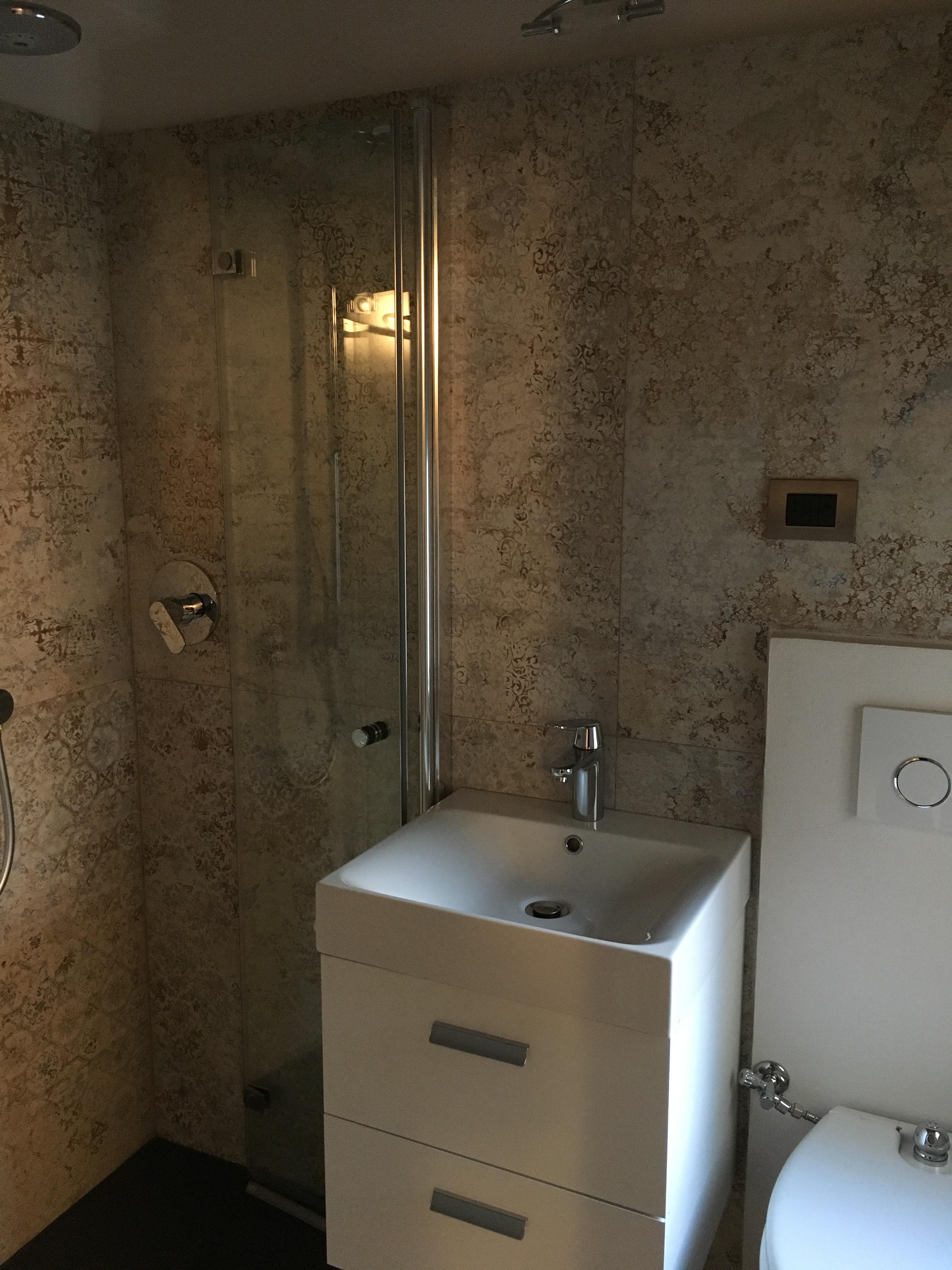 Piccolo bagno composto da doccia a livello del pavimento, lavamani e WC con tavoletta bidet