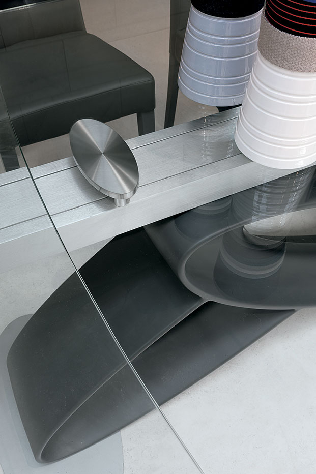 Tavolo allungabile in alluminio con basamento in poliuretano e piano in vetro temperato.