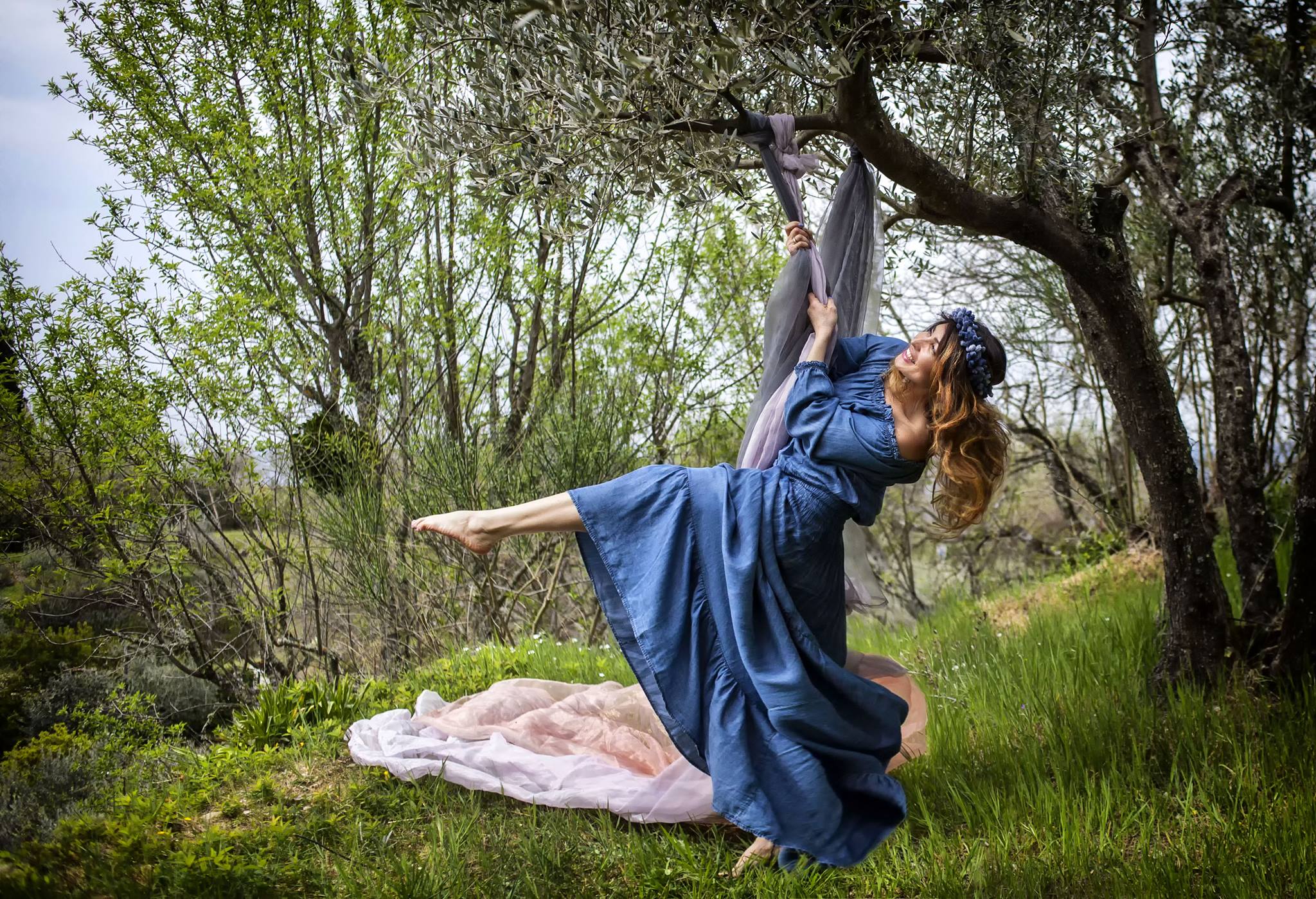 donna su altalena in un prato  in Toscana, fra  alberi di olivi