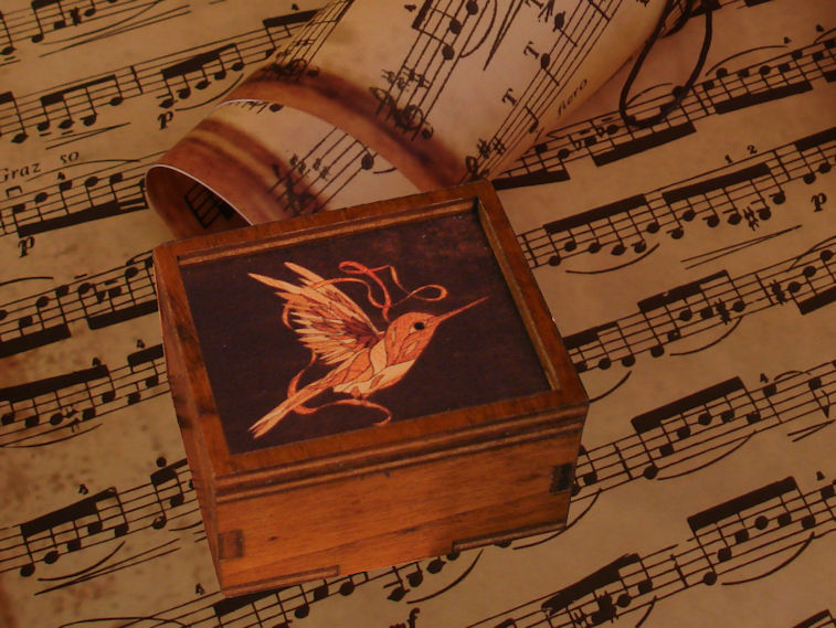 Piccolo music-box carillon con immagine di colibrì su una pagina di spartito musicale
