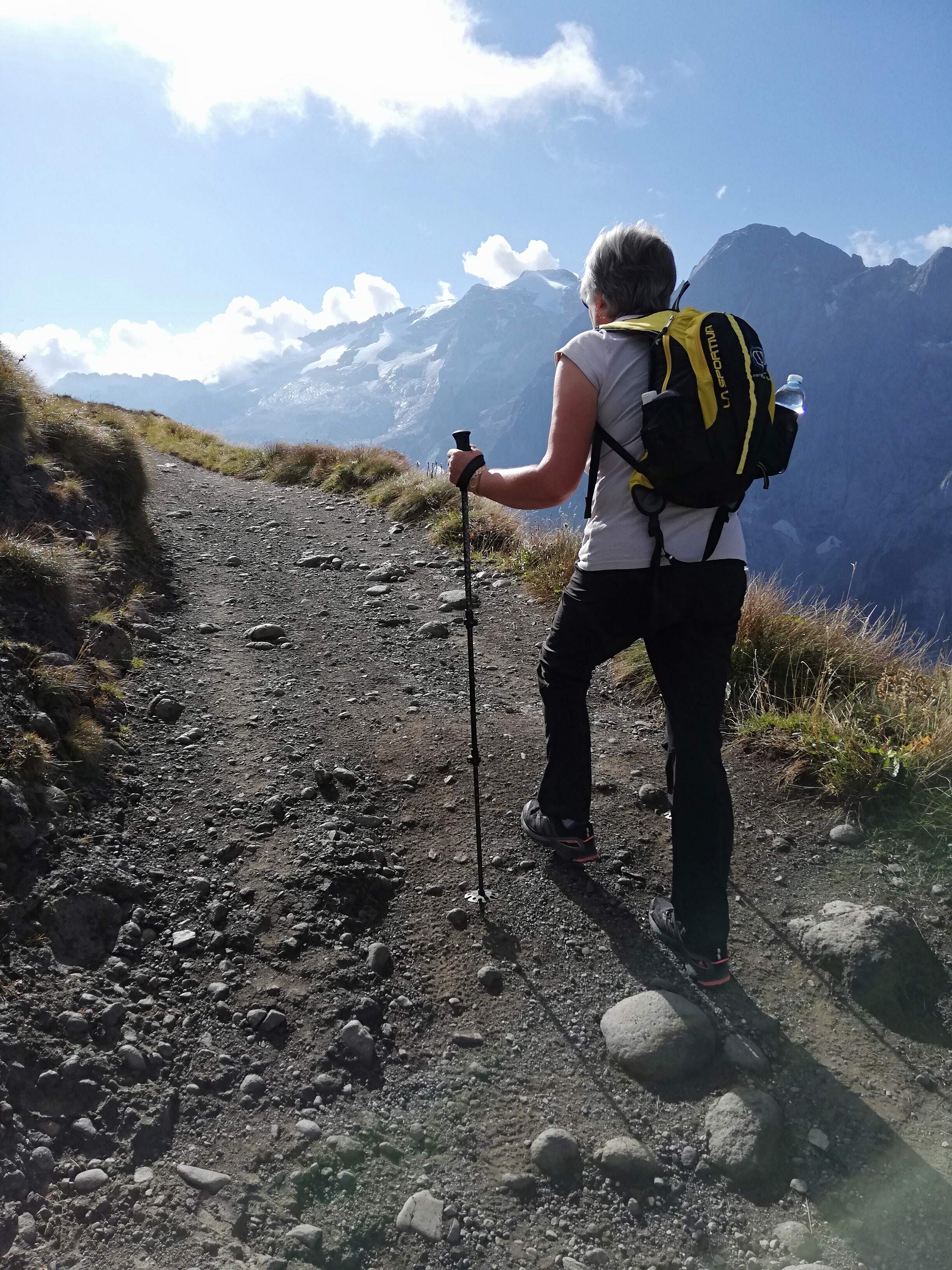 Escursionista con bastoni da trekking che affronta sentiero sterrato in montagna